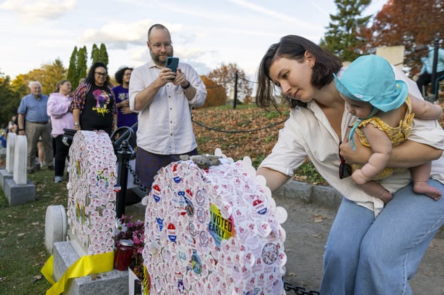Katie Guinta holings her six-month-old daughter, Margot, as she places an &#34;I voted&#34; sticker on the headstone of Susan B. Anthony at Mount Hope Cemetery in Rochester, New York on Election Day, Tuesday, Nov. 5, 2024.