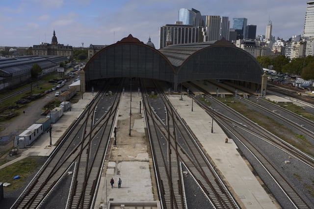 Two workers walk alongside empty railroad tracks at the Retiro train station during a general strike against the austerity measures of President Javier Milei in Buenos Aires, Argentina, Thursday, April 10, 2025. (AP Photo/Rodrigo Abd)