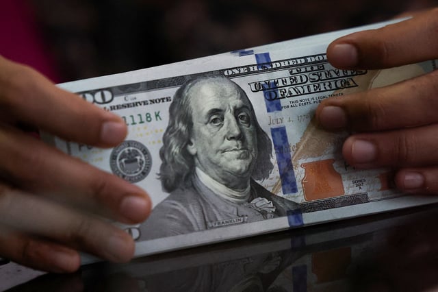 An employee holds U.S. dollar bank notes at a money changer in Jakarta, Indonesia, April 9, 2025. REUTERS/Willy Kurniawan/File Photo