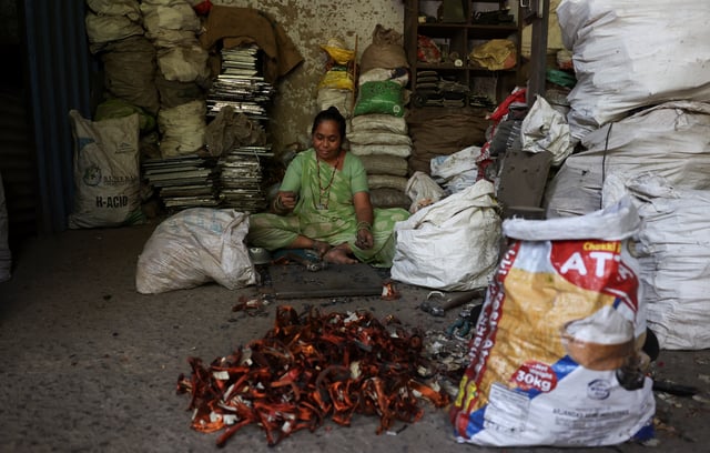 A woman separates copper and plastic from TV components at a scrap yard in Ahmedabad, India, April 9, 2025.REUTERS/Amit Dave
