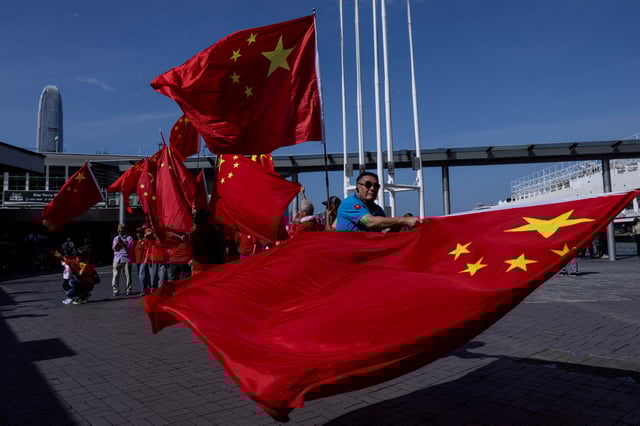 Chinese supporters wave Chinese national flags to celebrate the 75th anniversary of China's National Day in Hong Kong, China October 1, 2024. REUTERS/Tyrone Siu