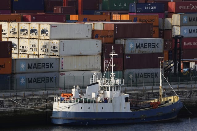 A boat is moored next to piled shipping containers at the port of Lisbon on the Tagus river, at dawn Wednesday, April 9, 2025. (AP Photo/Armando Franca)