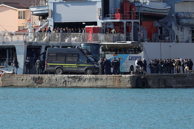 Members of the Italian and Albanian police gather, as a migrant disembarks from the Italian navy ship Libra, carrying migrants as part of a deal with Italy to process asylum-seekers caught near Italian waters, upon arrival in Shengjin, Albania, April 11, 2025. REUTERS/Florion Goga