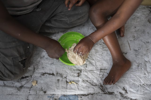 FILE - Women and children eat Tuesday, Feb. 18, 2025 in a Goma, eastern Congo school where they found shelter after their soldier husbands and fathers were sent to Rumangabo for mixing and integration into the M23 rebel forces. (AP Photo/Moses Sawasawa, File)
