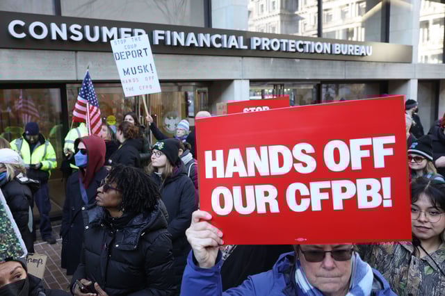 Demonstrators raise signs and posters during a rally outside the Consumer Financial Protection Bureau headquarters in Washington, DC, on February 10, 2025.