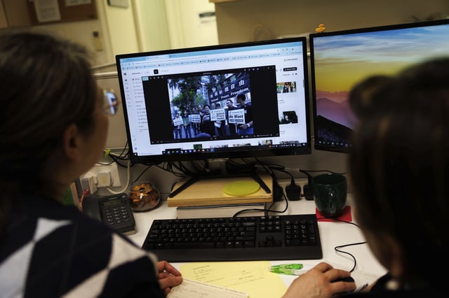 Emily Lau, former chairperson of the Democratic Party, right, looks through old photos with a staffer at the Democratic Party's office in Prince Edward in Hong Kong on April 2, 2025. (AP Photo/May James)