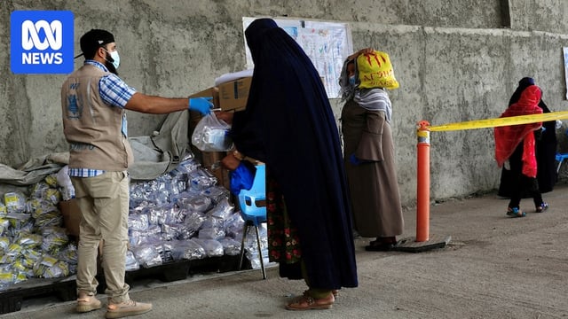 A woman clad in a burkha takes an aid package from a UN worker in Afghanistan.