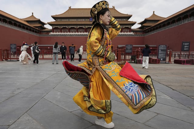 A woman dressed as the dowager reacts to strong winds outside the Forbidden City which was closed due to gale wind alerts in Beijing, China, Saturday, April 12, 2025. (AP Photo/Ng Han Guan)