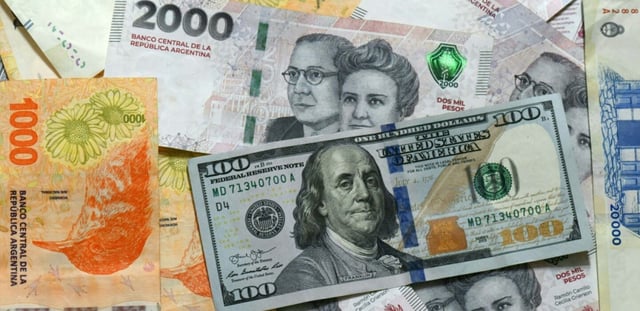 Des billets de pesos argentines et un billet de 100 dollars, le 11 avril 2025 à Buenos Aires