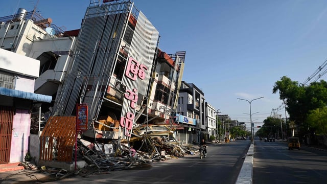 A man on motorcycle rides past a damaged building in Mandalay on April 13, 2025, following the devastating March 28 earthquake. Thousands marked the start of Myanmar's water festival on April 13 in the ruins of last month's earthquake, with the country's most raucous holiday muted by the tragedy of the tremor. 
