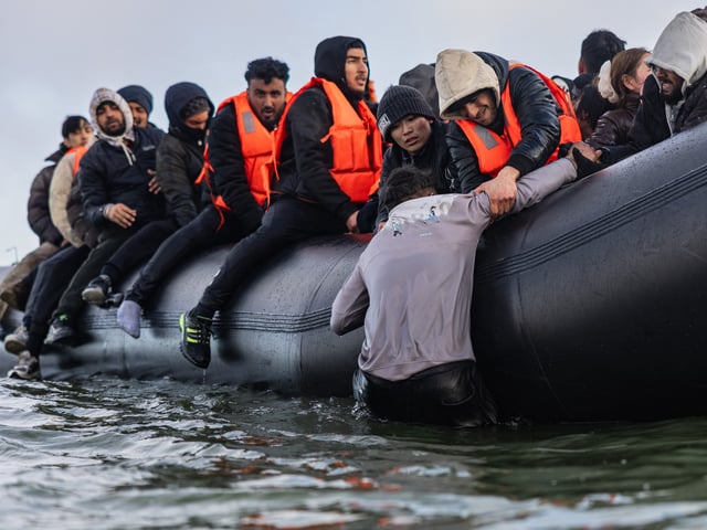 Migrants board a smuggler's boat in an attempt to cross the English Channel, off the beach of Gravelines, north of France, on March 26, 2025. (Photo by Sameer Al-DOUMY / AFP)