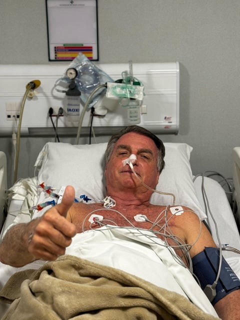 Former Brazilian President Jair Bolsonaro gestures as he lies in a bed in Rio Grande Hospital, in Natal, Brazil, in this social media picture obtained by Reuters on April 12, 2025. Jair Bolsonaro via X via REUTERS/File Photo