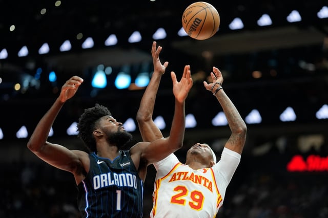 Atlanta Hawks guard Daeqwon Plowden (29) and Orlando Magic forward Jonathan Isaac (1) chase a rebound during the first half of an NBA basketball game, Sunday, April 13, 2025, in Atlanta. (AP Photo/Mike Stewart)
