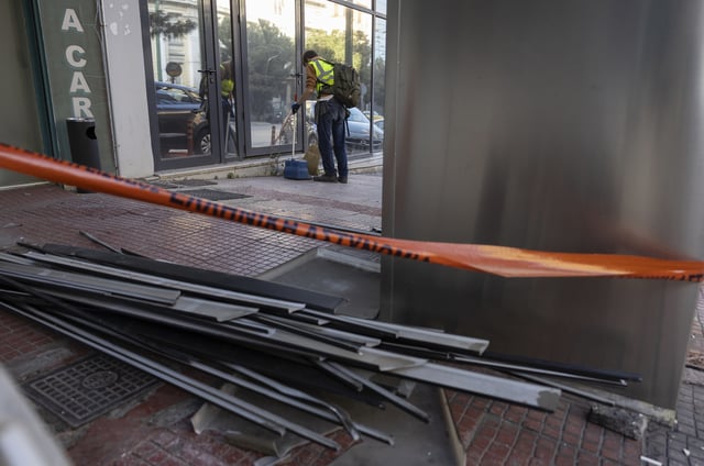 A municipal worker cleans the area outside Hellenic Train headquarters, Greece's main railway company, following a bomb explosion Friday night causing causing limited damage but no injuries, in Athens, Greece, on Saturday, April 12, 2025. (AP Photo/Yorgos Karahalis)