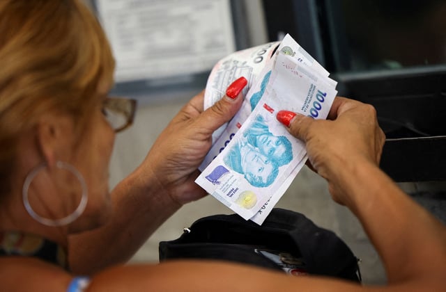 A customer counts Argentine peso bills before checking out in a supermarket, in Buenos Aires, Argentina January 13, 2025. REUTERS/Agustin Marcarian/File Photo