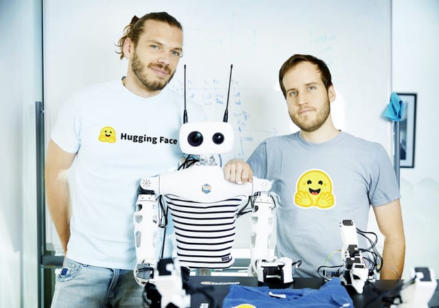 Hugging Face robotics and AI  researchers Simon Alibert and Rémi Cadene pose next to Reachy 2, the humanoid robot made by Pollen Robotics. Hugging Face announced today that is it buying Pollen Robotics for an undisclosed amount. The move marks Hugging Face&#39;s first move into offering hardware.