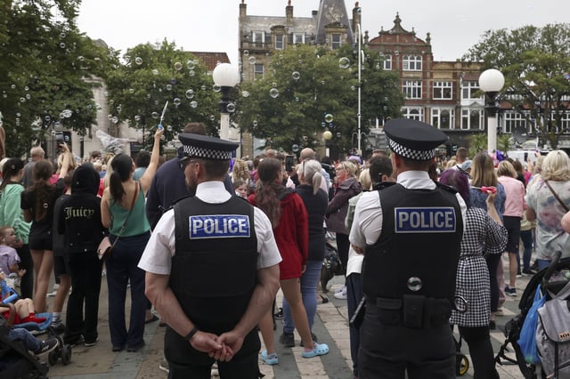 FILE - Police officers watch members of the public outside the Town Hall during a vigil to remember the victims of the stabbing attack last Monday in Southport, England, Monday, Aug. 5, 2024. (AP Photo/Darren Staples, File)