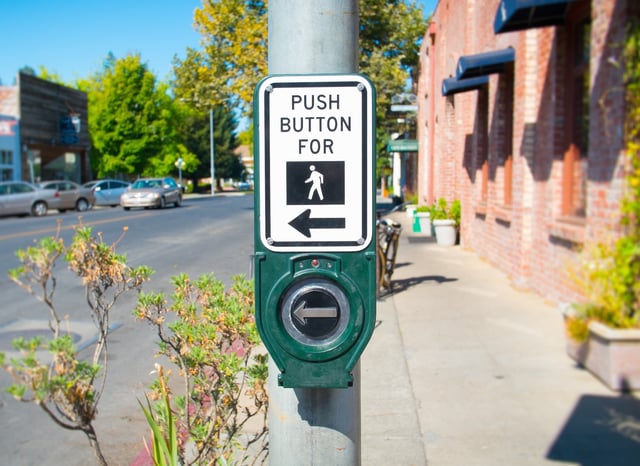 a photo of a crosswalk button that reads, "push button for"... and the symbol for walking.