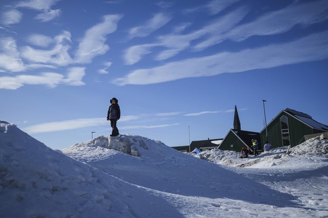 A girl stands on a snow outside a polling station during parliamentary elections in Nuuk, Greenland, on March 11, 2025.