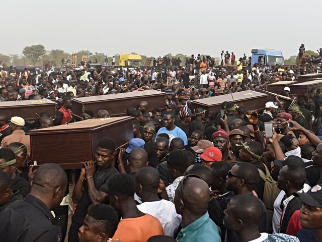 TOPSHOT - Pall bearers carry coffins during the funeral service for people killed during clashes between cattle herders and farmers, on January 11, 2018, in Ibrahim Babangida Square in the Benue state capital Makurdi. - Violence between the mainly Muslim Fulani herdsmen and Christian farmers has claimed thousands of lives across Nigeria's central states over the past few decades. The conflict is being driven by an increasing need for resources -- primarily land and water -- and is often exacerbated by ethnic and sectarian grievances. (Photo by PIUS UTOMI EKPEI / AFP) (Photo by PIUS UTOMI EKPEI/AFP via Getty Images)