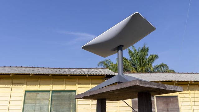A Starlink broadband satellite dish sitting on a table outside a house.
