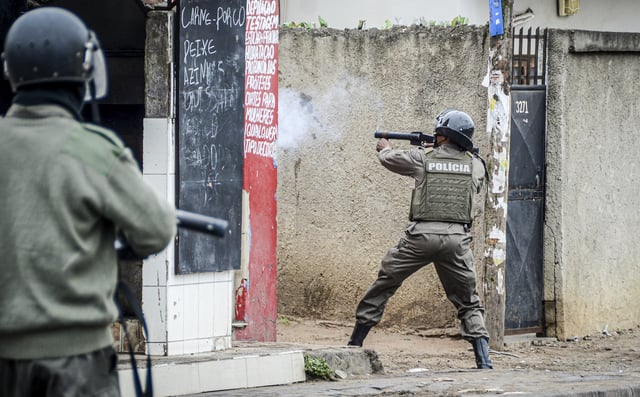 FILE - A police officer aims his weapon at protesters in Maputo, Mozambique, Thursday, Nov. 7, 2024. Protesters dispute the outcome of the Oct. 9 elections that saw the ruling Frelimo party extend its 49-year rule. (AP Photo/Carlos Uqueio, file)