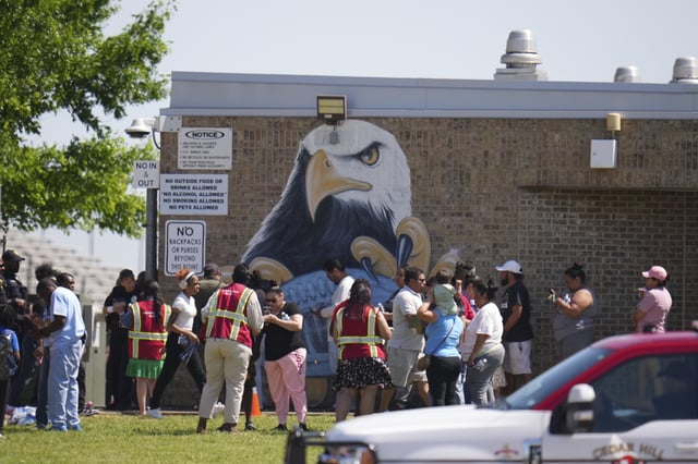 Parents are checked in to pick up their children at Wilmer-Hutchins High School, where police are responded to reports of a shooting in Dallas, Tx., Tuesday, April 15, 2025. (AP Photo/Julio Cortez)