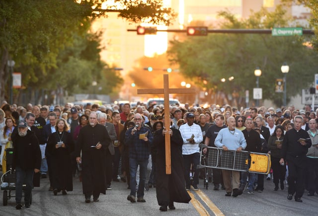 Parishioners participate in the Stations of the Cross pilgrimage, led by Father David Svihel carrying a wooden cross, walk down main street in downtown Sarasota, Florida on April 7, 2023.