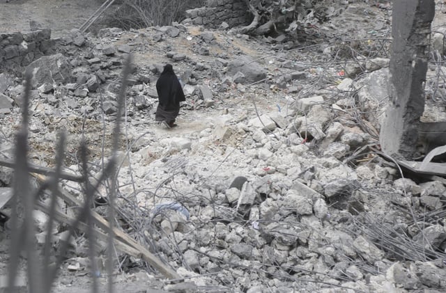 A woman walks near a building struck by a US aerial attack on Sunday night and left one passerby killed and five others injured, on March 24, 2025 in Sana&#39;a, Yemen.