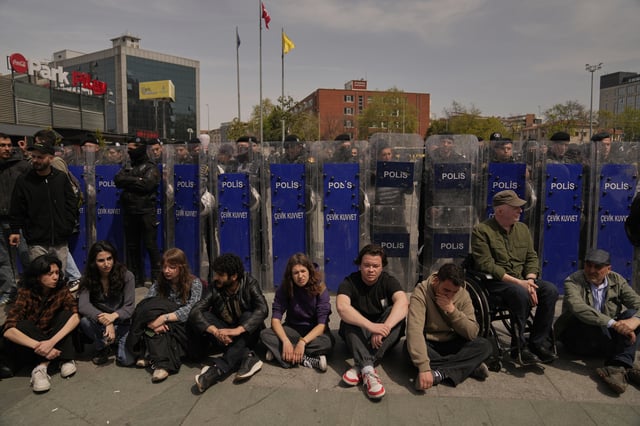 People sit next a police security line during a protest outside Caglayan courthouse, in Istanbul, Turkey, Friday, April 18, 2025, during the hearing of dozens of people accused of attending banned demonstrations after the arrest of Istanbul's Mayor Ekrem Imamoglu. (AP Photo/Khalil Hamra)