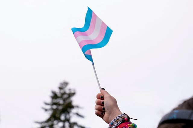A demonstrator holds a trans flag during a rally in support of trans youth at Seattle Children’s hospital, following U.S. President Donald Trump’s executive order that denies federal funding for pediatric gender-affirming care, in Seattle, Washington, U.S. February 8, 2025. REUTERS/David Ryder/File Photo