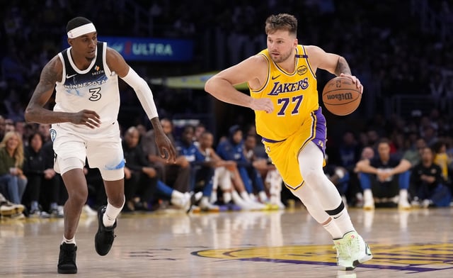 Los Angeles Lakers guard Luka Doncic, right, dribbles by Minnesota Timberwolves forward Jaden McDaniels during the second half of an NBA basketball game, Thursday, Feb. 27, 2025, in Los Angeles. (AP Photo/Mark J. Terrill)