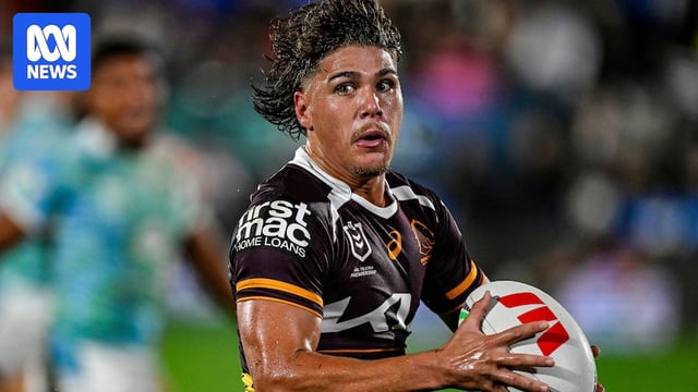 Reece Walsh looks to pass while carrying a white ball with blue jerseys behind him
