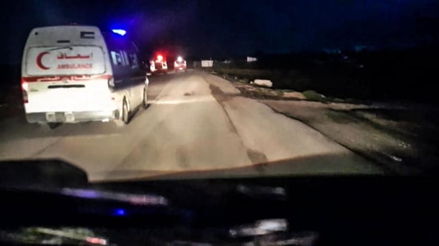 Ein Krankenwagen des Palästinensischen Roten Halbmonds fährt mit Blaulicht durch die Dunkelheit.