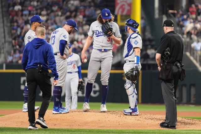 Dodgers infielders, umpire Nic Lentz, right, and a team staff member check on starting pitcher Tyler Glasnow, who left the game with an unknown injury, in the fifth inning of a baseball game against the Texas Rangers in Arlington, Texas, Sunday, April 20, 2025. (AP Photo/Tony Gutierrez)