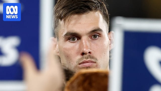 Sam Darcy looks miserable as he is framed by the coach's whiteboards during a Western Bulldogs AFL game.
