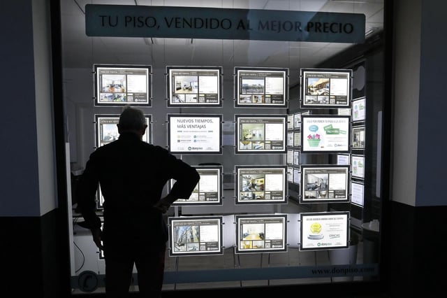 Un hombre mira los carteles de pisos en una inmobiliaria de València.