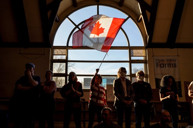 A supporter waves a flag as Canada's Prime Minister Mark Carney speaks during his Liberal Party election campaign tour in Fredericton, New Brunswick Canada April 21, 2025. REUTERS/Carlos Osorio