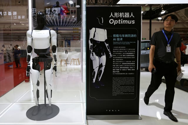 A man walks past Tesla's humanoid robot Optimus displayed at the World Robot Conference in Beijing, China August 21, 2024. REUTERS/Florence Lo