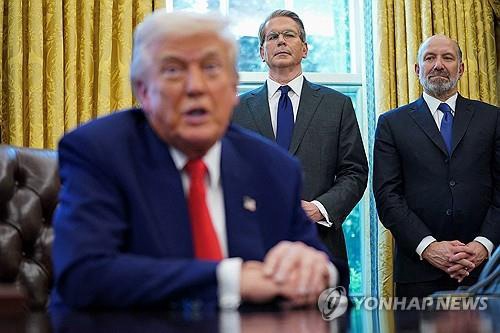 This Reuters' file photo shows U.S. Commerce Secretary Howard Lutnick (R) and Secretary of the Treasury Scott Bessent (C) stand as President Donald Trump signs executive orders and proclamations in the Oval Office at the White House in Washington on April 9, 2025. (PHOTO NOT FOR SALE) (Yonhap)