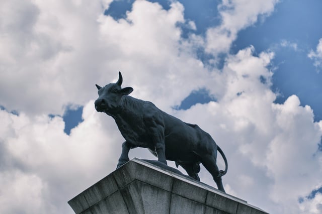 A statue of a bull on a platform outlined against a cloudy sky in South Korea.