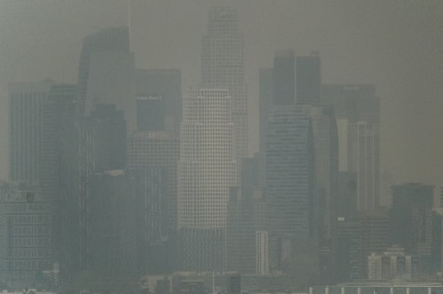 File photo: Thick heavy black smoke from wildfires shrouds buildings in downtown Los Angeles on Wednesday, January 8, 2025.