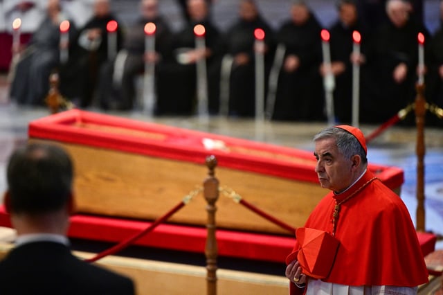 Giovanni Angelo Becciu walks next to the coffin after paying his respects during a ceremony inside St Peter&#39;s Basilica following the procession of the late Pope&#39;s coffin from the chapel of Santa Marta to St Peter&#39;s Basilica, in the Vatican on April 23, 2025.