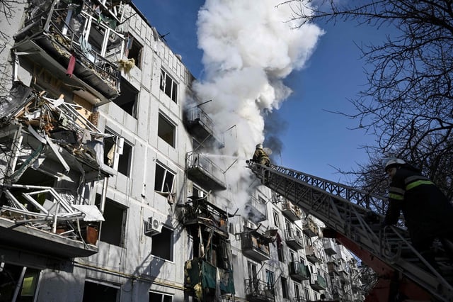 Firefighters work on a fire on a building after bombings on the eastern Ukraine town of Chuguiv on February 24, 2022, as Russian armed forces are trying to invade Ukraine from several directions, using rocket systems and helicopters to attack Ukrainian position in the south, the border guard service said.