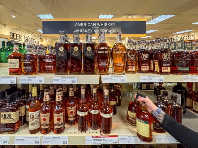A worker places bottles of American whiskey into a shopping cart to fill an order for a restaurant, at a Liquor Control Board of Ontario (LCBO) store in Hamilton, Ontario, Canada February 2, 2025.  REUTERS/Carlos Osorio/File Photo