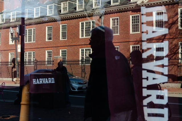 Harvard University is reflected in the window of a merchandise store across the street from the university's campus.