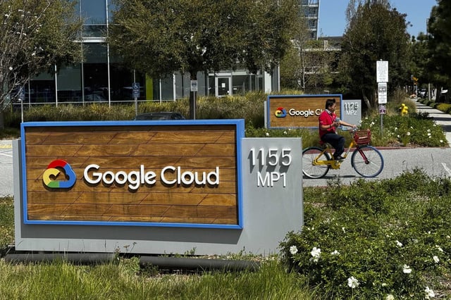 A person rides past the Google sign outside the company’s offices in Sunnyvale, Calif., in 2024. The tech titan is asking employees to return to the office, or face being fired.