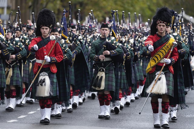 A pipe band marches past thousands of people lining the street to pay tribute to their war dead during the Anzac Day parade in Sydney, Australia, Friday, April 25, 2025. (AP Photo/Rick Rycroft)