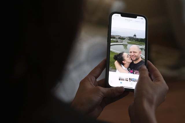 Oksana Tarasiuk holds a cell phone displaying a picture of herself, left, with her husband, Maksym Chernyak, who died in ICE custody after being held at Krome Detention Center, inside the couple's apartment in Hallandale Beach, Fla., Tuesday, April 22, 2025. (AP Photo/Rebecca Blackwell)