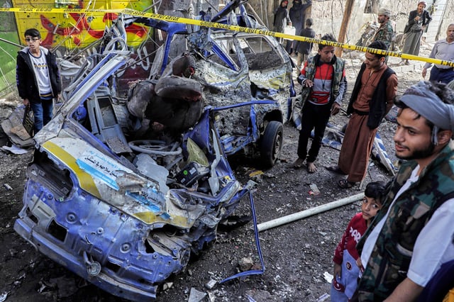 Yemenis watch a damaged vehicle at Farwah popular market which Houthis said it was struck by US airstrikes in Sanaa, Yemen, on April 21.